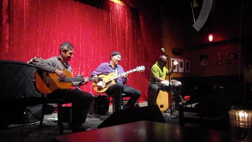 three men playing guitars and drum