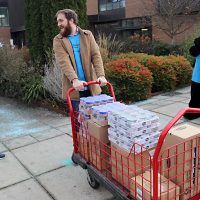 Students haul away food boxes to stock the pantry.