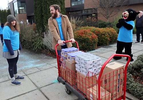 Students haul away food boxes to stock the pantry.