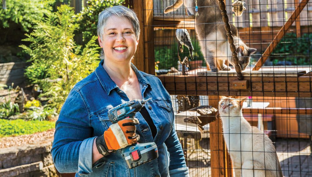 Woman in front of catio with cats.