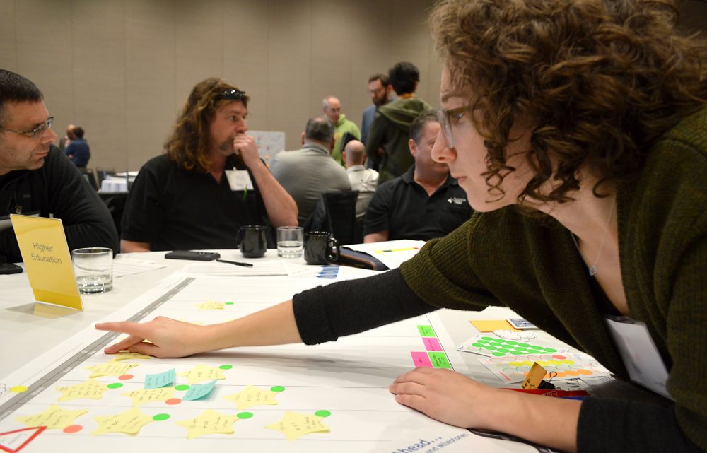 Anna Brown reaching across the table at a SEM workshop with