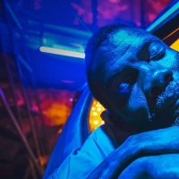 Photo of a sleeping man under bright blue lights, taken from one of the films