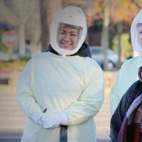 Health clinic workers wearing full protective equipment with a patient outside