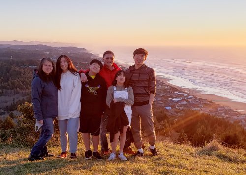 Family of six poses on a bluff overlooking the ocean