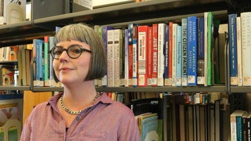 Woman standing in front of library stacks