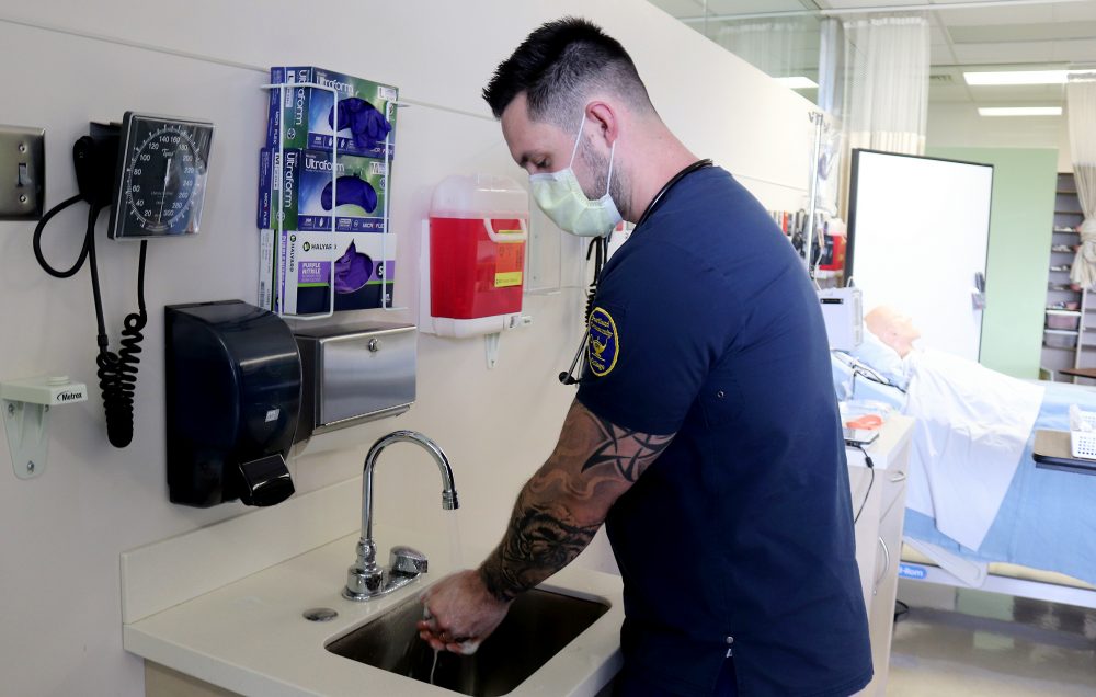 Nursing student washes his hands while wearing his mask.