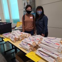 Two people standing behind a table. The table is filled with banhmi baguette sandwiches.