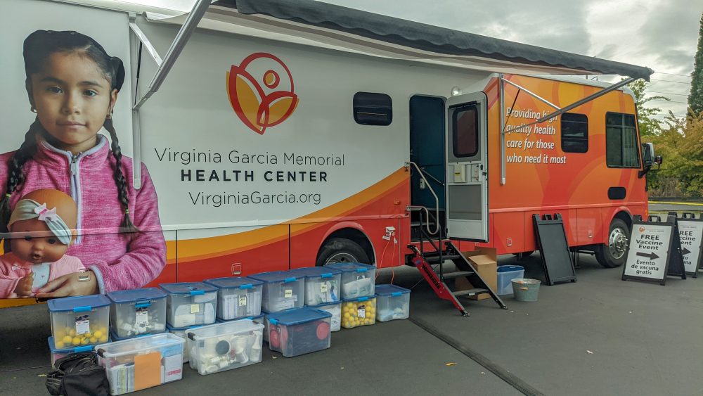 Mobile health truck with Virginia Garcia Memorial logo and a girl holding a doll