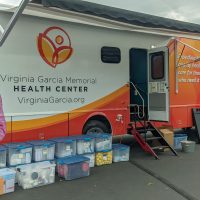 Mobile health truck with Virginia Garcia Memorial logo and a girl holding a doll