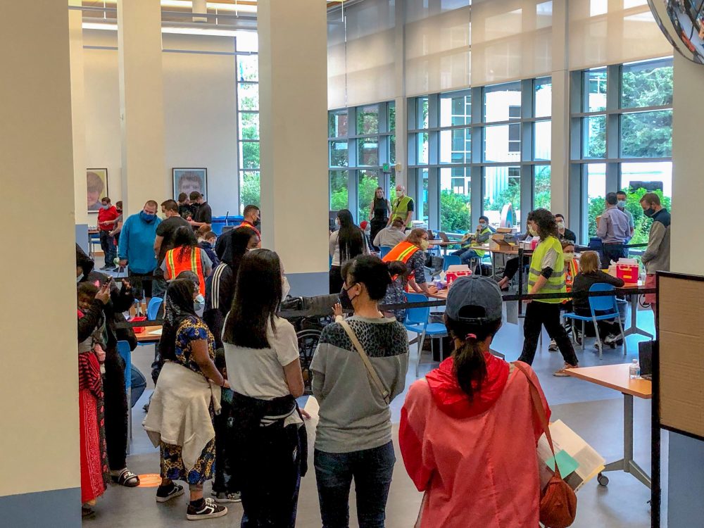 community members and health professionals in line and at tables getting vaccinated