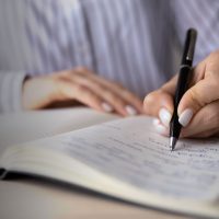 Crop close up of Caucasian woman sit at desk at home office write make notes in notebook. Female employee or worker handwrite in notepad, engaged in time planning or management. Habit concept.