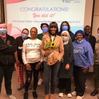 Tracee Wells holding flowers, stranding with group of students who completed the spring 2022 cohort
