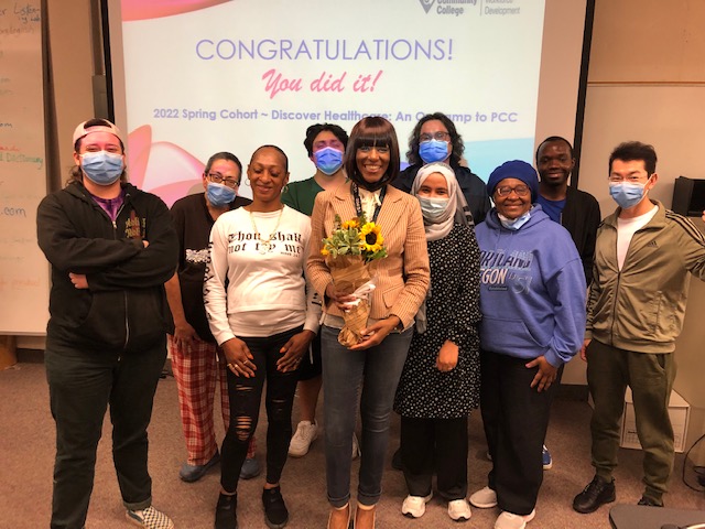 Tracee Wells holding flowers, stranding with group of students who completed the spring 2022 cohort