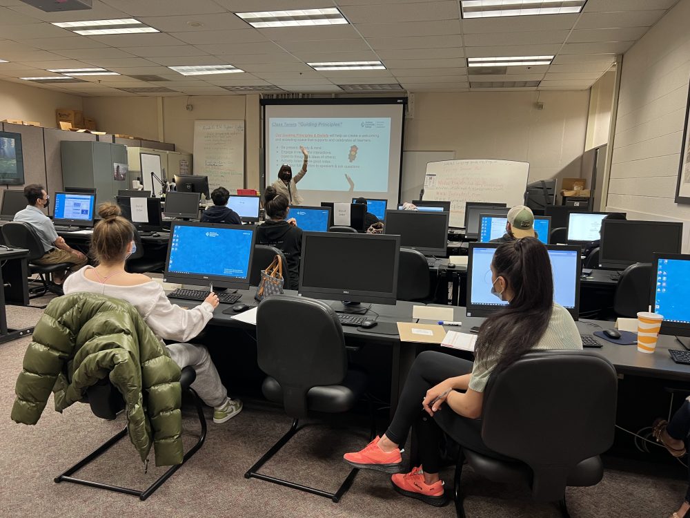 Tracee Wells standing at the front of a classroom filled with students and computers