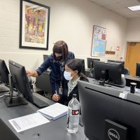 Tracee Wells standing at a computer assisting a student