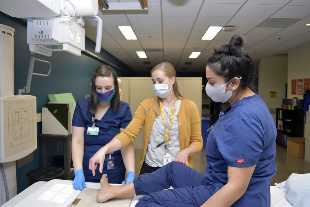 Program chair Jennifer Bringhurst (center) provides pupils Taylor Walters (left) and Utahana Rosales a lesson in foot anatomy.