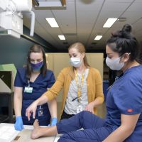 Program chair Jennifer Bringhurst (center) provides pupils Taylor Walters (left) and Utahana Rosales a lesson in foot anatomy.