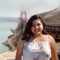 woman smiling with San Francisco's Golden Gate Bridge in the background