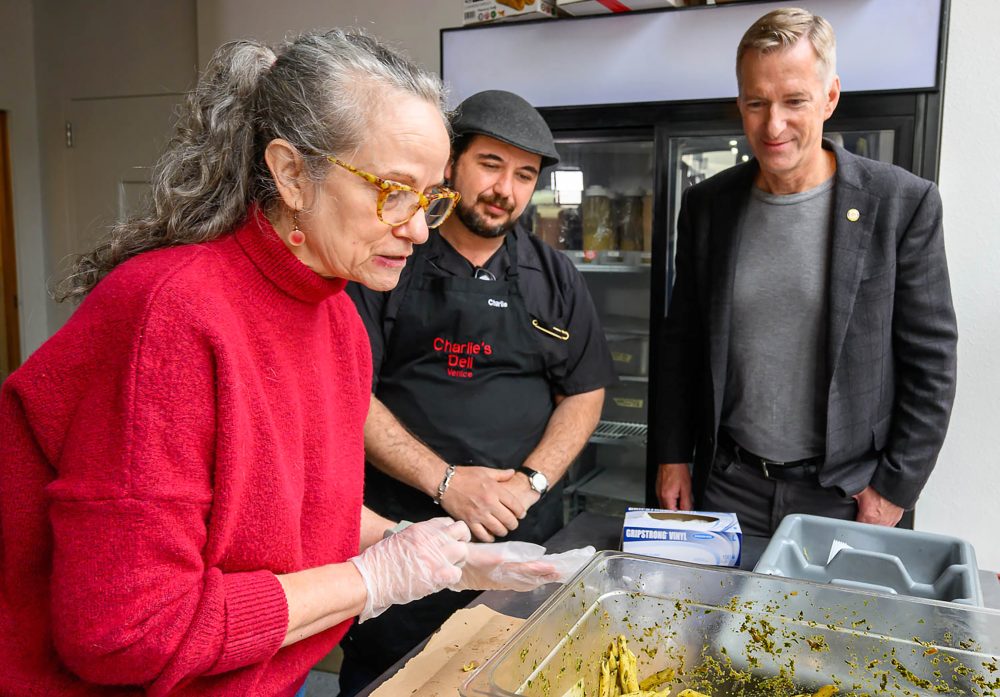 Deborah Mustard at work while boss and Mayor Wheeler watch.