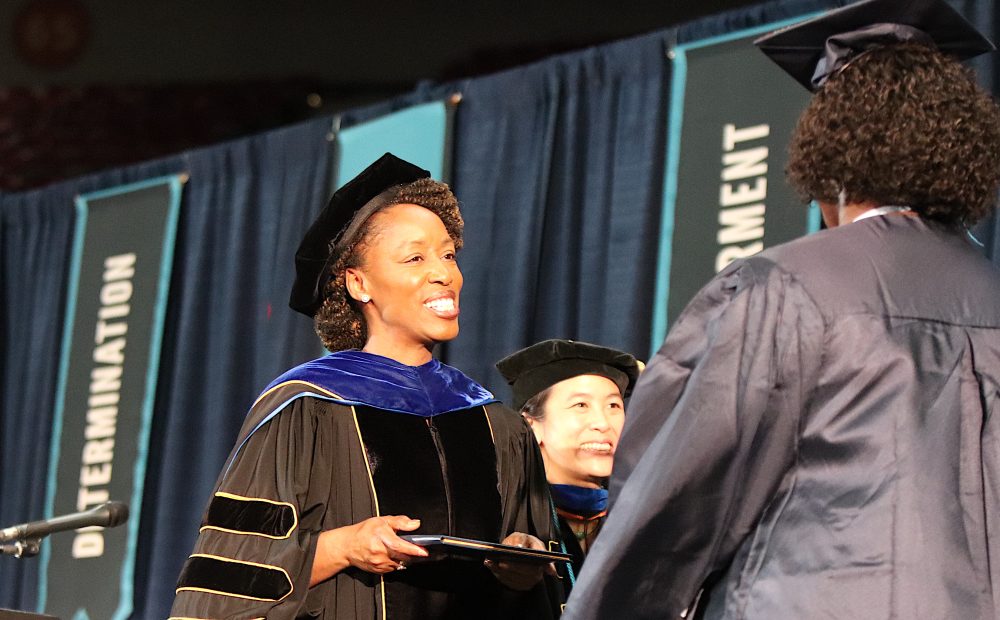 Dr. Bennings hands a diploma to a happy graduate.