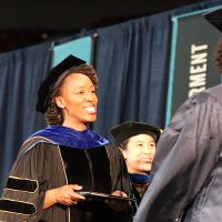Dr. Bennings hands a diploma to a happy graduate.