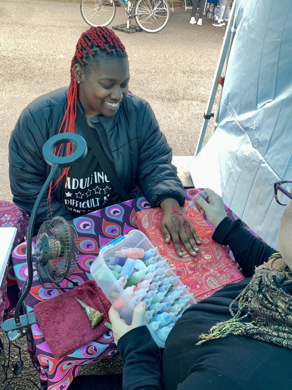 Student getting colorful henna design on her hand.