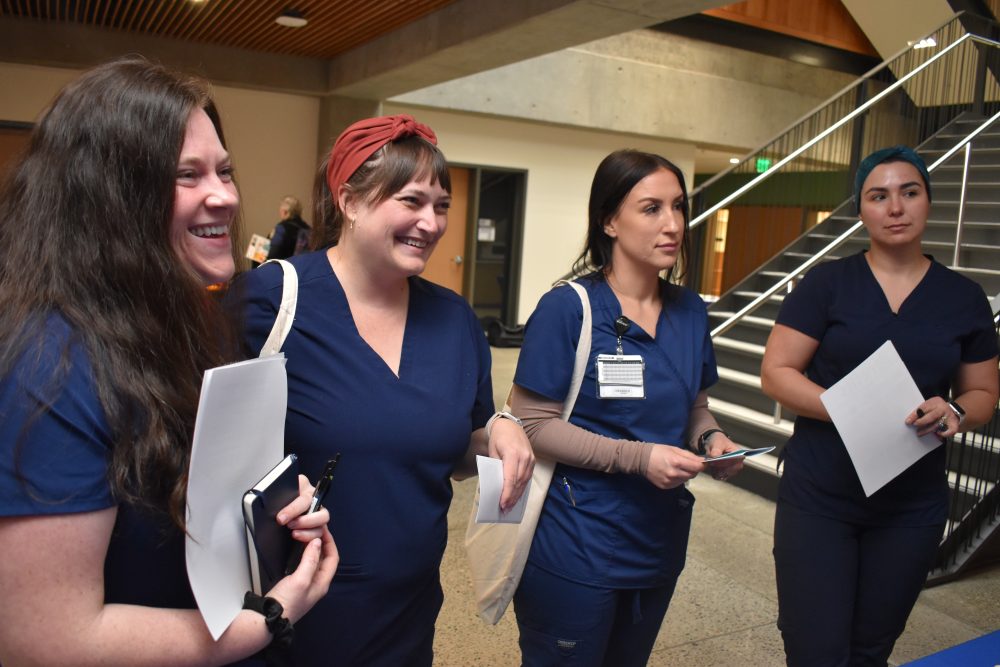 Four nurses in scrubs attend event.