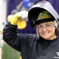 Juanita flexes in welding garb