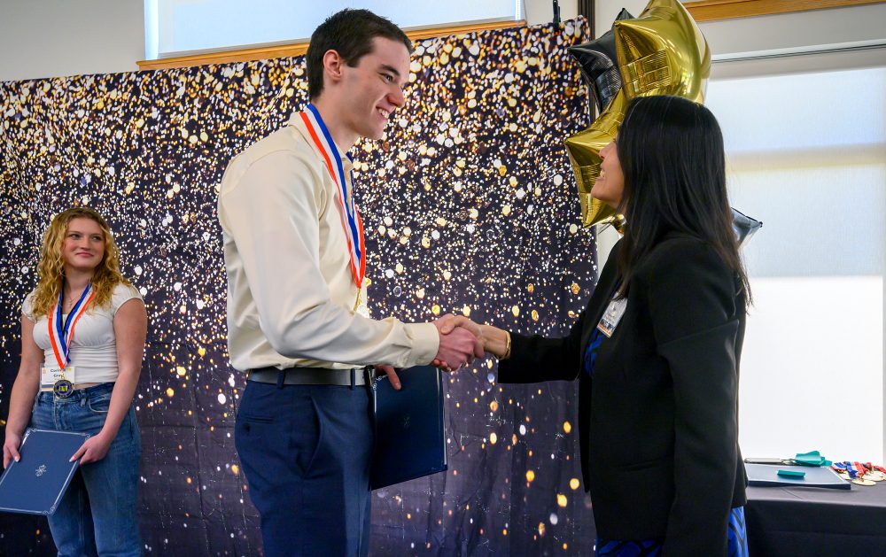 Scholar Jesse Hauck receives congratulations from Vice President of Academic Affairs Katy Ho.