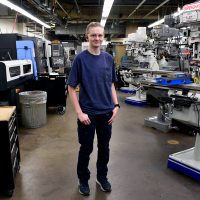 Kennedy Godfrey standing in Sylvania machining shop.