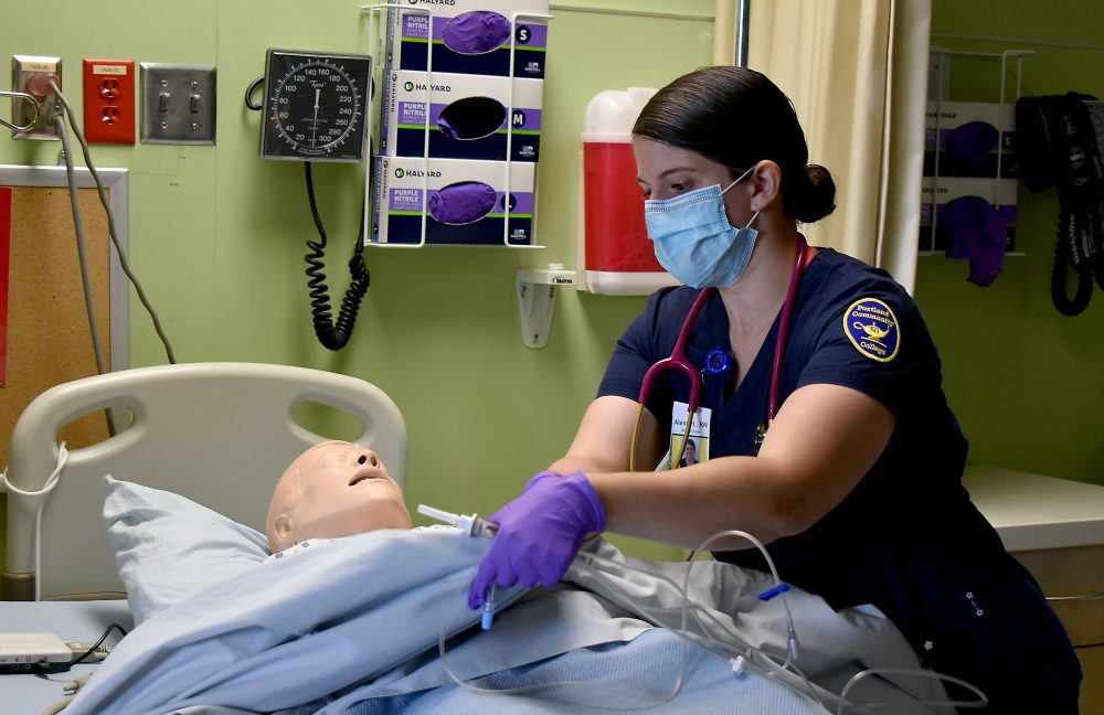 Nursing student practicing patient care with robot.