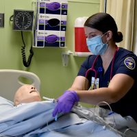 Nursing student practicing patient care with robot.