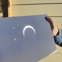 Hand on reflective surface featuring an image of the solar eclipse.
