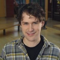 Smiling college student in flannel shirt.