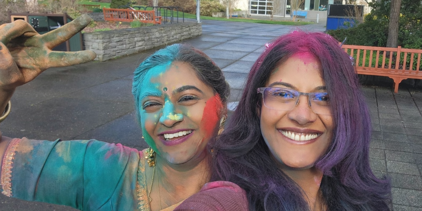 Two women taking a selfie covered in holi colors.