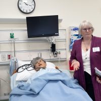 Program Dean for Health & Emergency Professions Lisa Regan-Vienop demonstrates a nursing manikin.