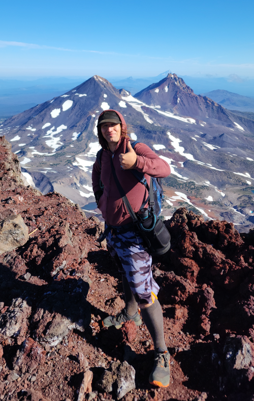 Man stands before Central Oregon snow-capped mountain peaks.