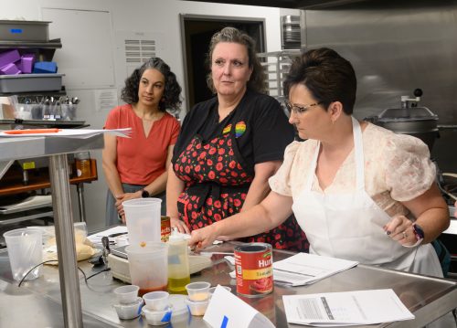 Katrina Stein observes Hillsboro School District culinary arts and hospitality instructors Melissa Buechler and Kristi Moe at the PCC CTE Summit in a commercial kitchen.