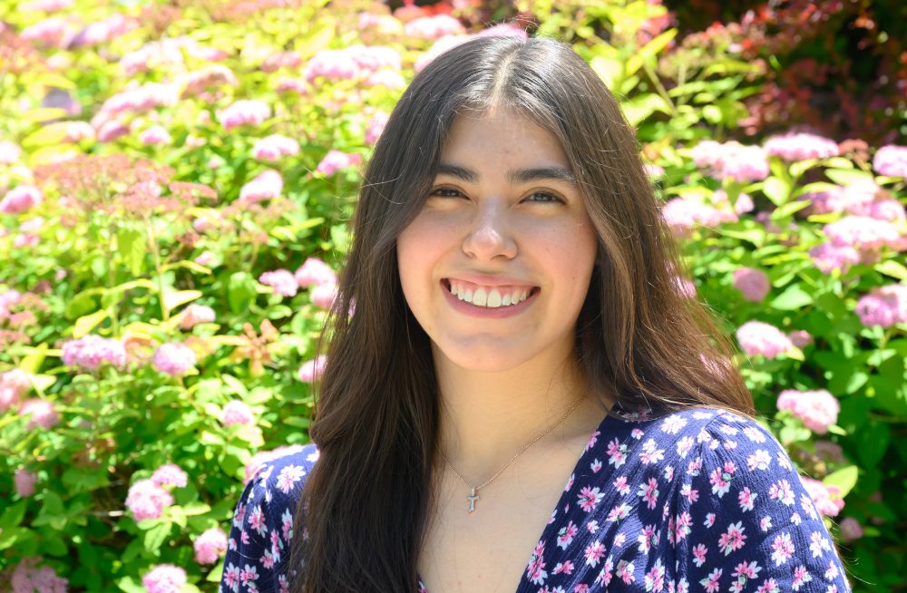 Lizbeth Ramos posing outside by bushes.