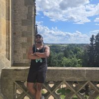 Black young man stands between historic buildings in Europe.