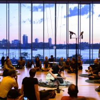 City in background of crowd gathered around sound musician at Whitney Museum.