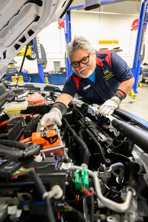PCC Automotive Service Program alum Rick Cruz works on the new EV vehicle used for SHIFT training in the Sylvania Campus shop.
