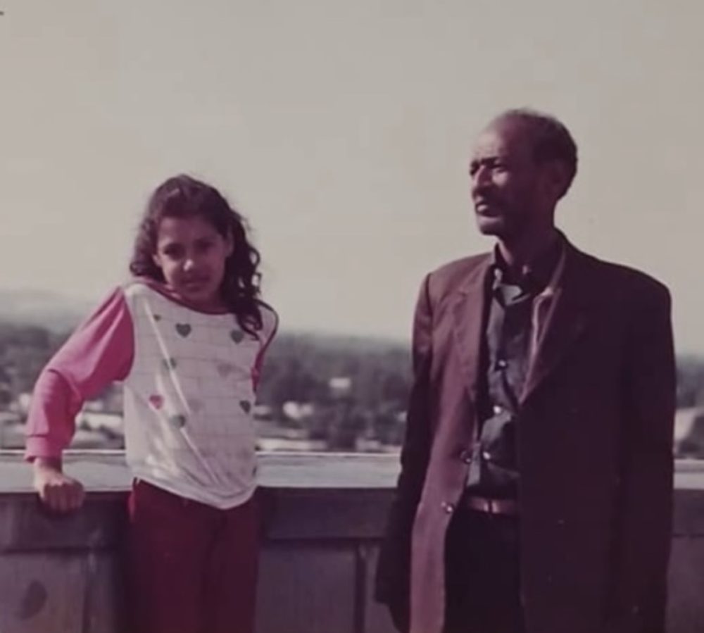 Small girl and grandfather appear in vintage photo.