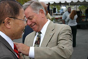 Portland Mayor Tom Potter, a PCC grad himself, pins a City of Portland button on PCC Board Member Jaime Lim. Lim had pinned Potter with a PCC lapel pin earlier.