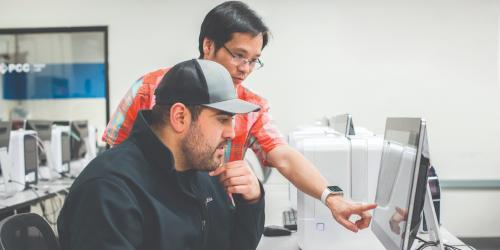 Two males looking at a computer as they search the web