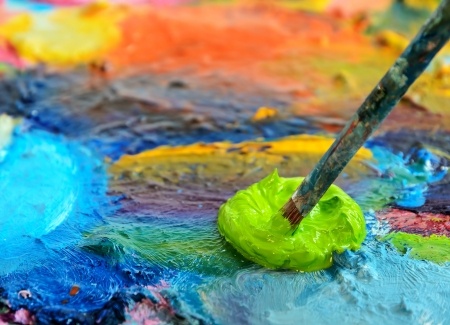 Picture of palette with mixture of paint colors and paintbrush.