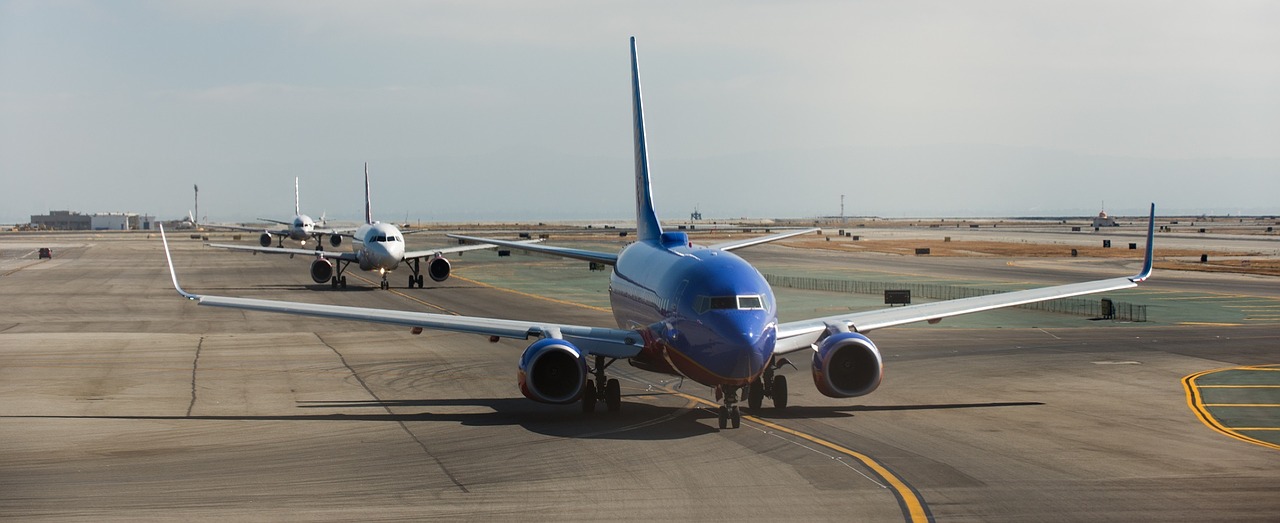 several airplanes queued up for takeoff on a runway.