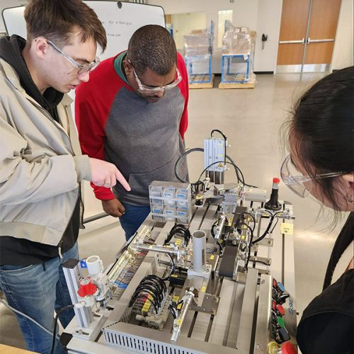Three students learning in a manufacturing space