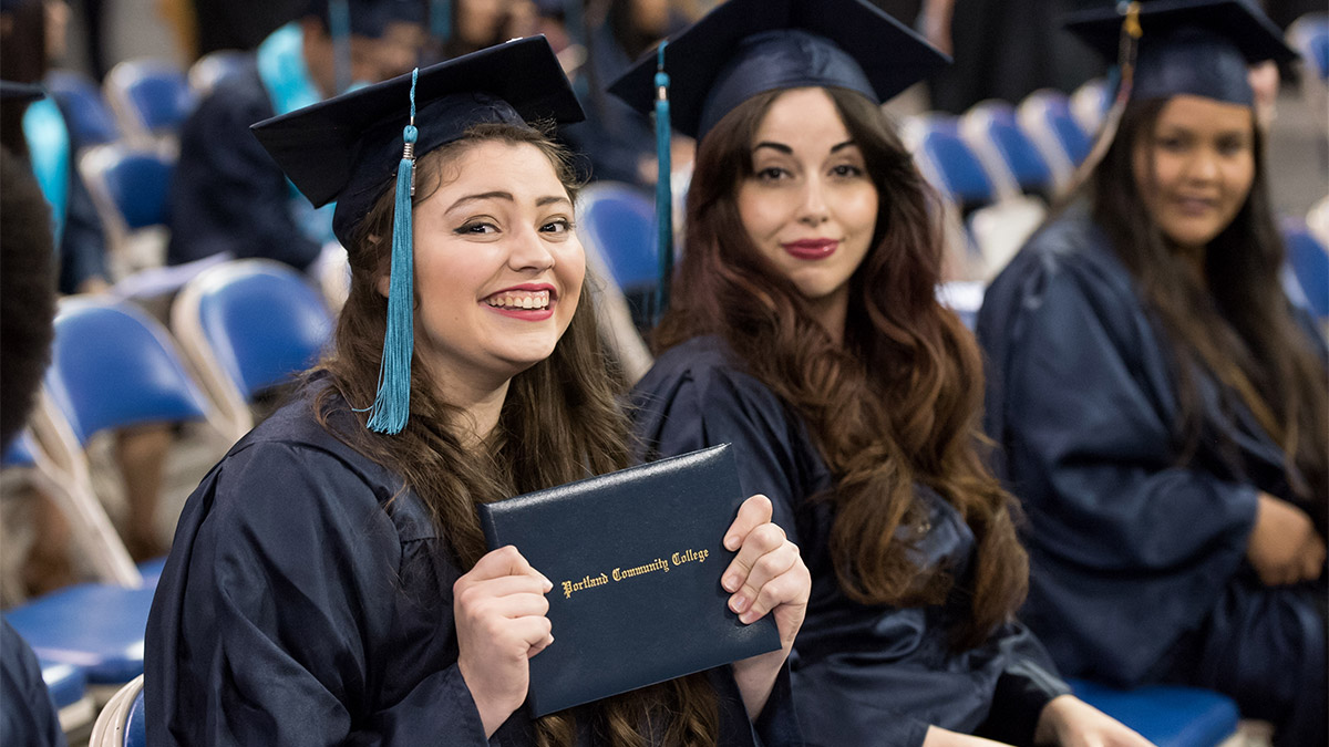 Graduates at commencement holding their diplomas