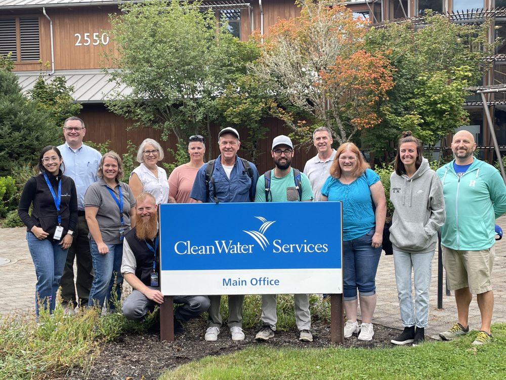 Group of educators attending an externship opportunity standing behind a Clean Water Services logo